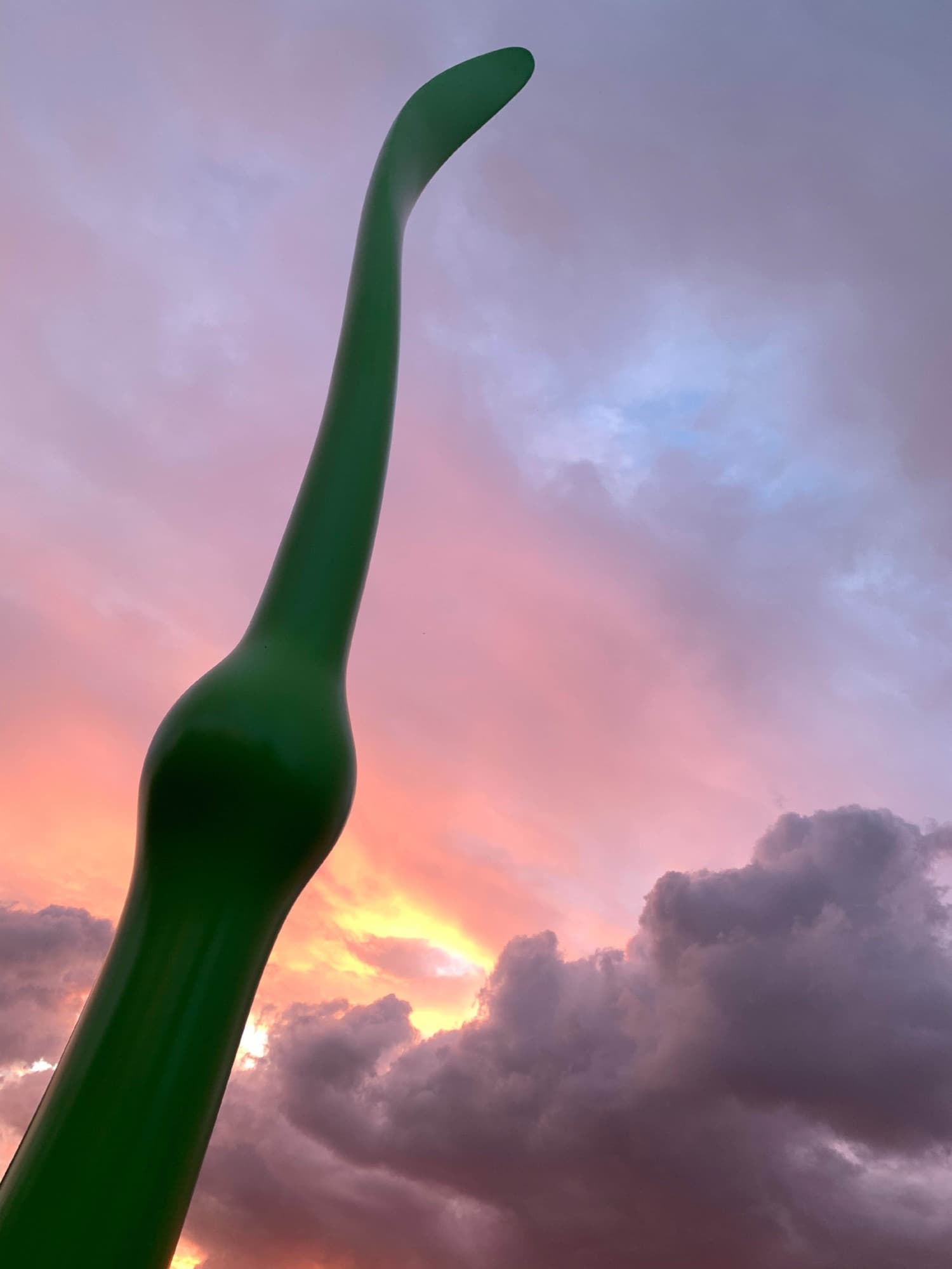 Green Life, curved tip against a pink sunset sky