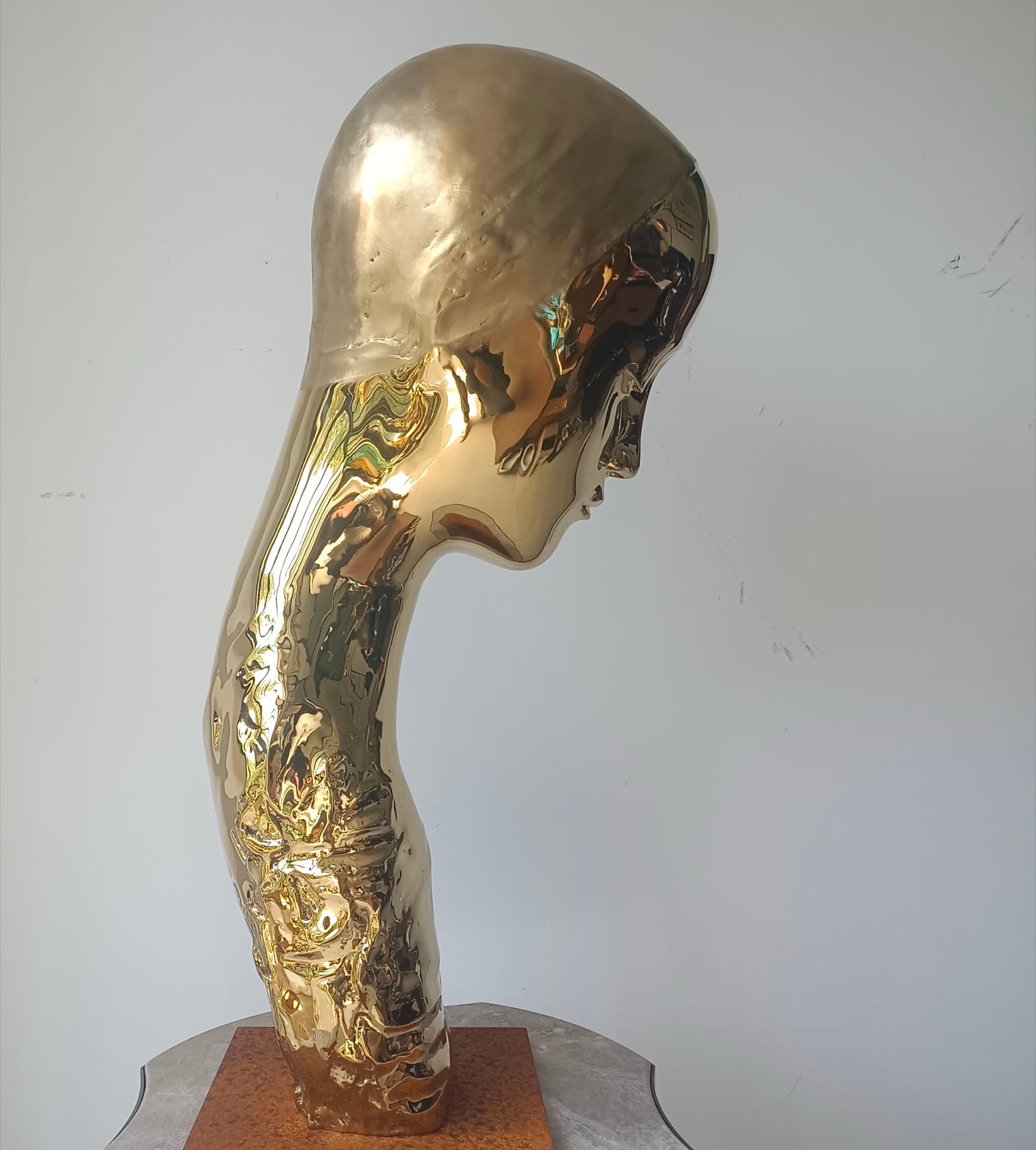Mariam, mirror-polished golden head and neck on a rusted steel base, side view