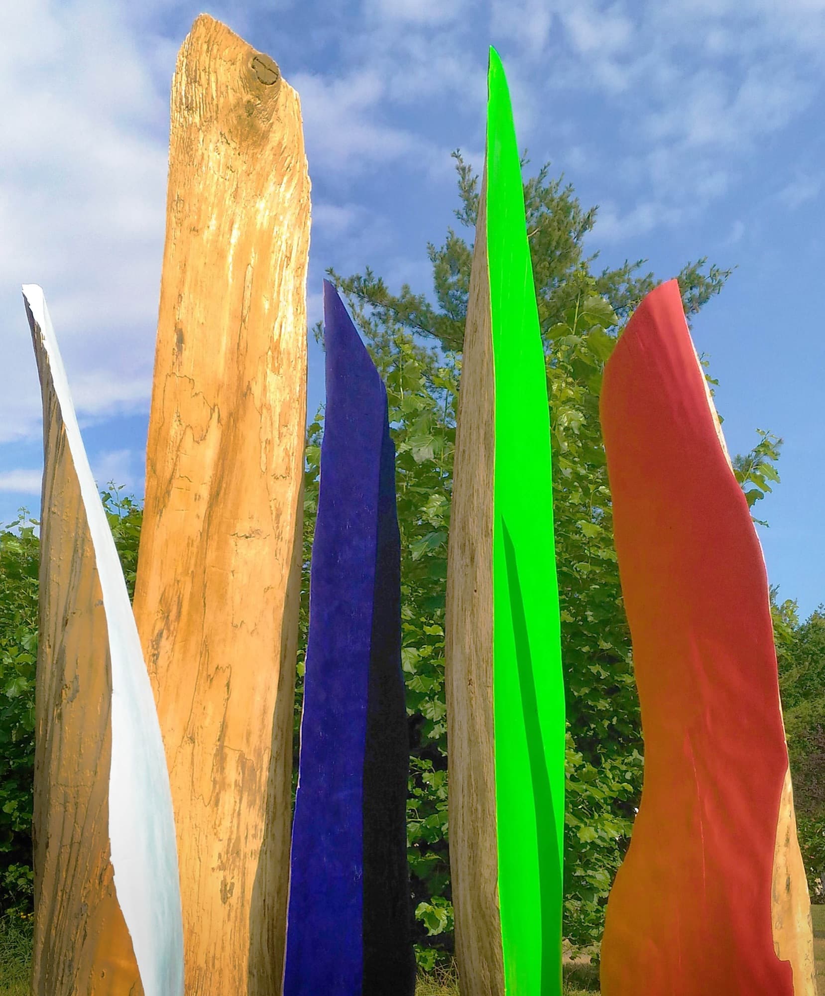 12, group of wooden and painted forms outdoors against sky and trees