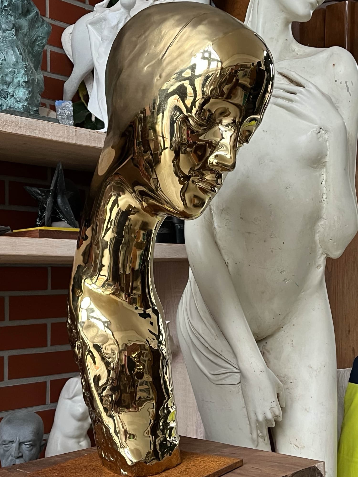 Mariam, golden polished head in the studio beside a white figure